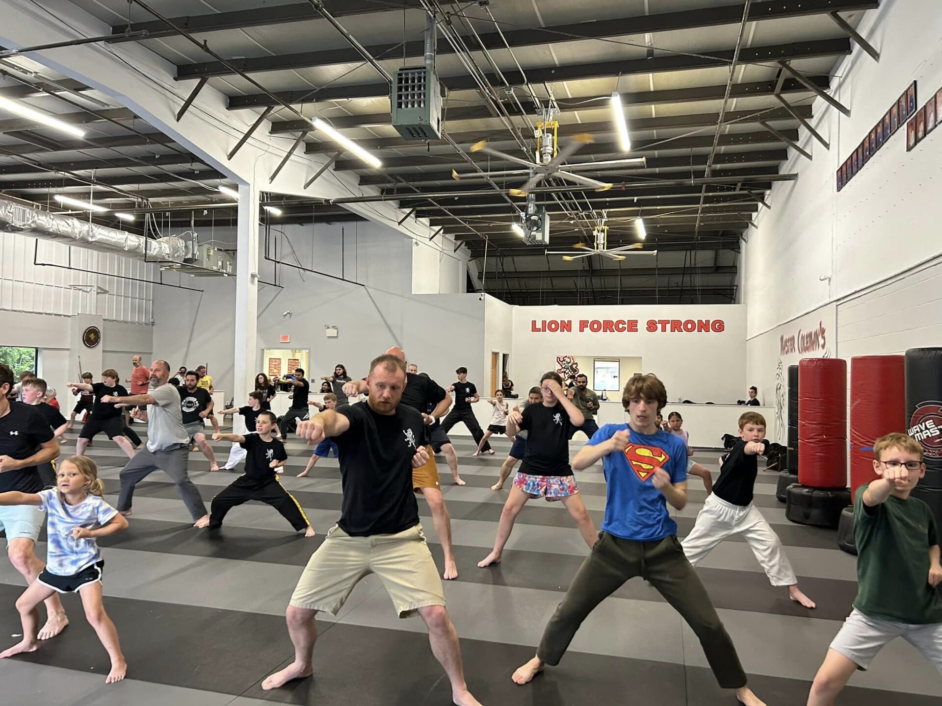 The group is standing on a mat, practicing their karate moves and techniques