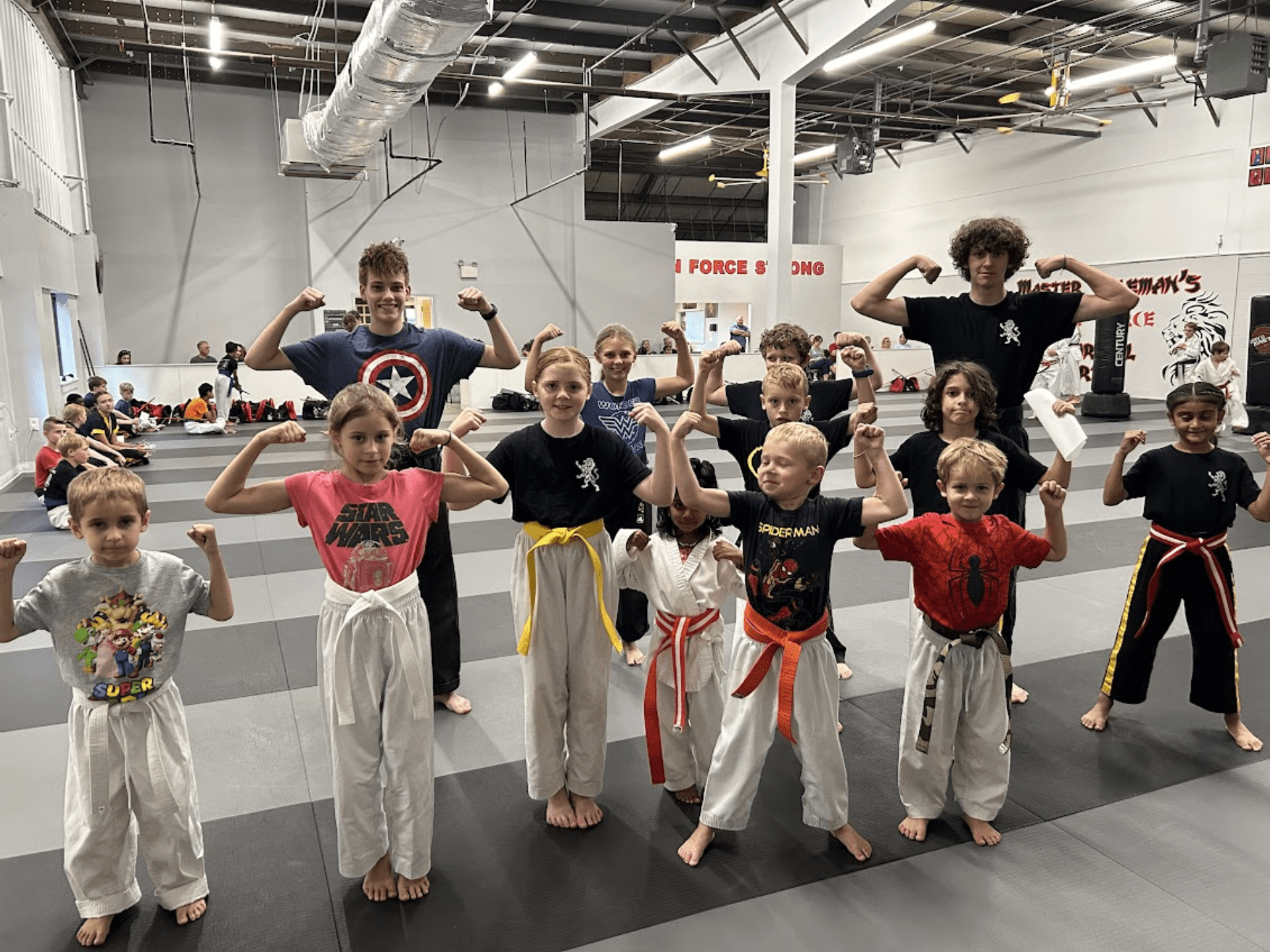 A group of kids dressed in martial arts uniforms smiles for a photo, highlighting their dedication and camaraderie